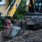 Sewer repair, excavated pit, excavator and drain cover