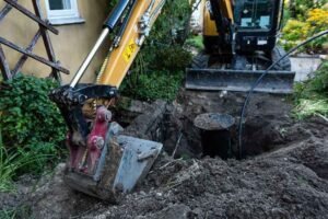 Sewer repair, excavated pit, excavator and drain cover